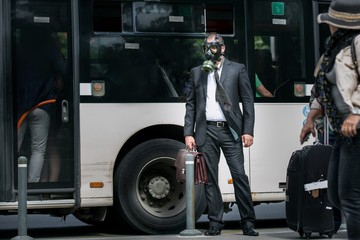 Fototapeta na wymiar Businessman in a bus station wearing a gas mask on the face.