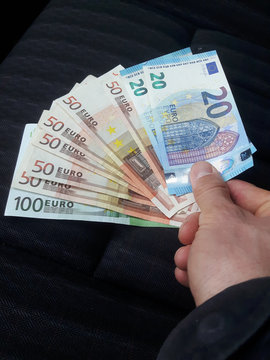 Mann h&auml;lt Geldscheine vor schwarzen Hintergrund