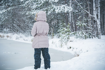 Child down on the frozen lake in winter forest