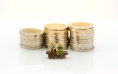 Miniature people, Old couple figure sitting on the chair with  stack of coins. Image use for background retirement planning, Life insurance concept.
