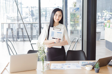 Asian beautiful young business woman in white shirt hand holding financial report document.