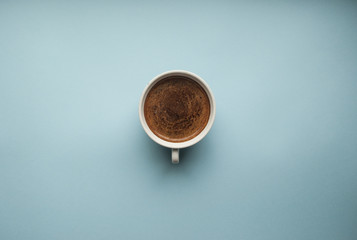 A cup of fresh coffee on blue background with text space.