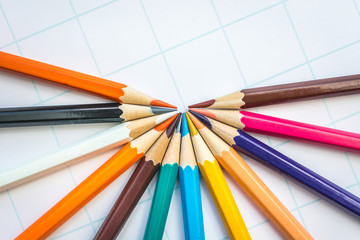 Naklejka premium Colored pencils laid out in a semicircle on a white sheet of paper