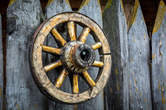 Old wooden cart wheel hanging on the fence