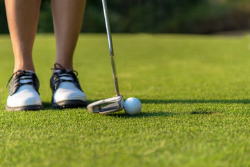 Golfer asian woman putting golf ball on the green golf on sun set evening time.  Healthy and...