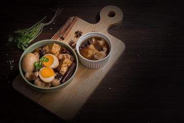 Pha-lo with dim light : Eggs boiled and pork boiled with spices and fried tofu in sweet gravy soup on wooden background with copy space © metha275