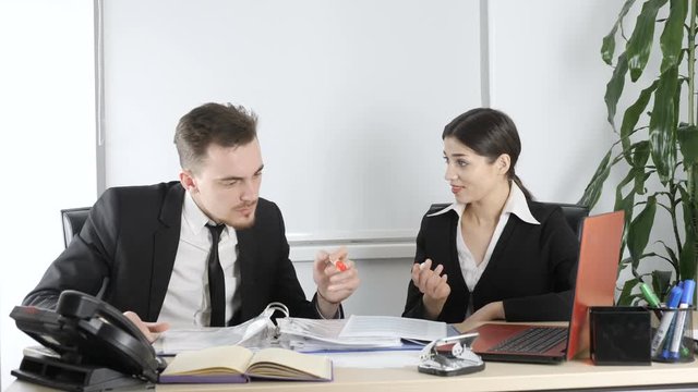 A young man and a woman in suits discuss a contract at the office. Business, office workers, deal 60 fps