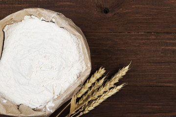 Paper package of wheat flour on a wooden background. Top view, copy space. Food background