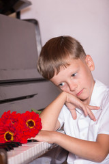 A young pianist man sits behind a piano with a bouquet of flowers. Concert of classical solo music..