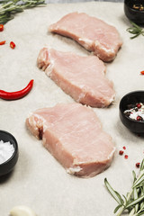 Raw meat with various spices on a gray background