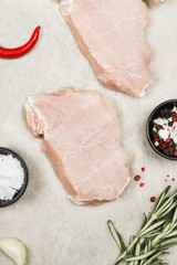 Raw meat with various spices on a gray background. Top view. Food background