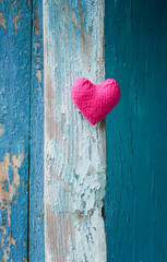 pretty pink heart made of yarn on a background of a wooden wall with blue peeling paint