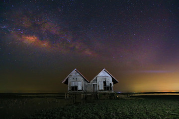 The milky way landscape with abandoned hut on field in Thailand,noise and grain picture style