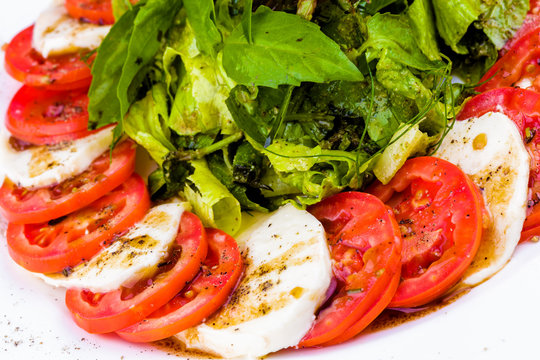 Caprese salad with spices and herbs on white plate