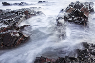The dramatic view of the wave splashed to the rock during sunrise