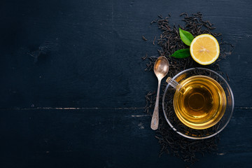 Tea in a glass cup with spices and herbs. On a black wooden background. Top view. Copy space.