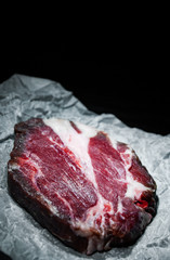 piece of raw meat beef steak on paper on dark wooden background with copy space.
