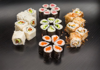 Sushi and roll set with seafood isolated on black wood background with reflection. Japanese cuisine.