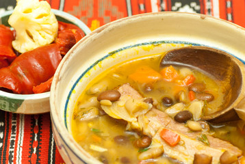 bowl with delicious bean soup with smoked meat and assorted pickles aside