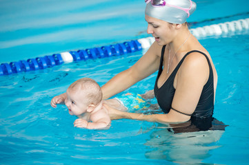 mother teach her baby, how to swim in a swimming pool