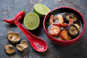 Red bowl with thai Tom Yum soup and some of its cooking components, selective focus, studio shot