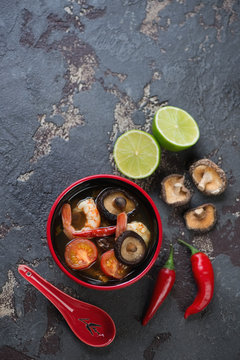 Tom Yum thai soup on a brown stone background, vertical shot with space, view from above