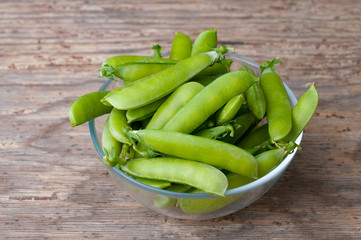 Green peas in bowl on wooden background