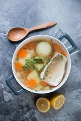 Fish soup or ukha with sudak in a bowl, top view on a grey concrete surface, vertical shot