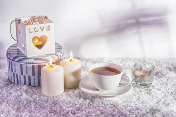wooden white candlestick, candles, cup of tea on white artificial snow