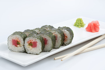 sushi or rolls in assortment on a long plate, wooden sticks, red ginger and wasabi