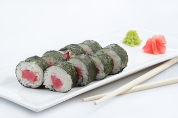 sushi or rolls with tuna on a long plate, wooden sticks, red ginger and wasabi