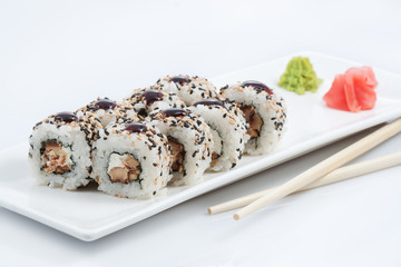 sushi or rolls in assortment on a long plate, wooden sticks, red ginger and wasabi