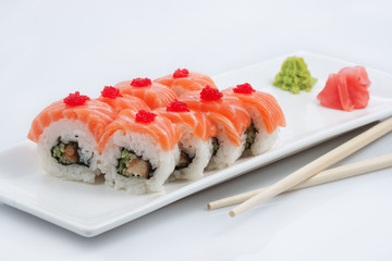 sushi or rolls in assortment on a long plate, wooden sticks, red ginger and wasabi