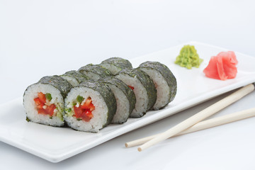 sushi or rolls in assortment on a long plate, wooden sticks, red ginger and wasabi