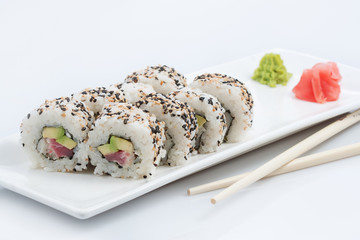 sushi or rolls in assortment on a long plate, wooden sticks, red ginger and wasabi