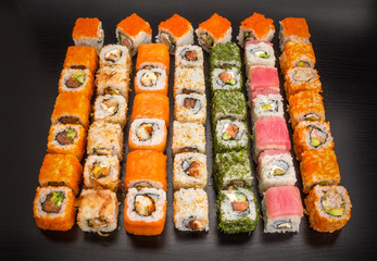 Sushi and roll set with seafood isolated on black wood background with reflection. Japanese cuisine.