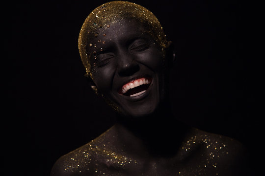 Portrait of a beautiful woman with creative body art glowing make up. Face is colored with black paint.