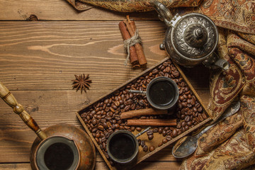 Turkish coffee in silver dishes with ground coffee and coffee beans, cinnamon, anise. On a wooden background.