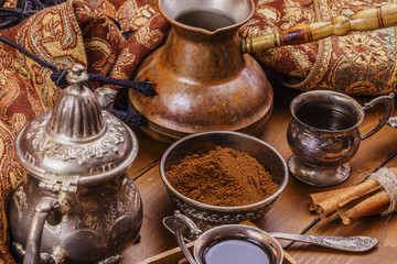 Turkish coffee in silver dishes with ground coffee and coffee beans, cinnamon, anise. On a wooden background.