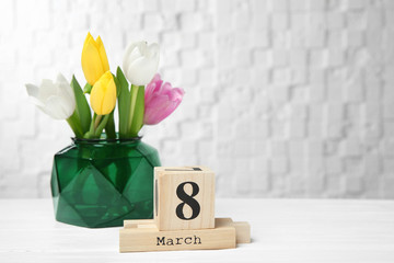 Vase with tulips and block calendar on table. Composition for International Women's Day