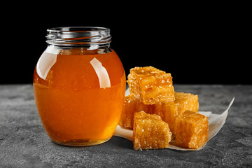 Aromatic honey in jar and honeycombs on table