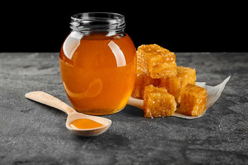 Aromatic honey in jar and honeycombs on table