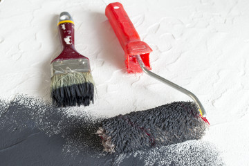 Brush and roller in black paint