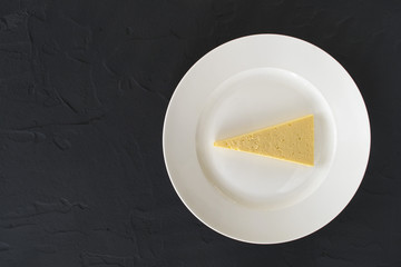 A piece of cheese on a white plate
