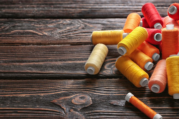 Set of color sewing threads on wooden background
