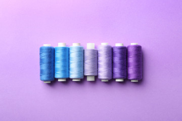Set of sewing threads on color background, top view