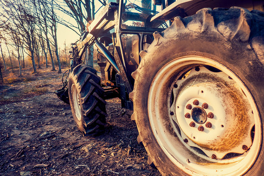 Tractor with crane in autumnal countryside, closeup on tyre