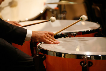 Obraz na płótnie Canvas Musician playing drums during a concert, closeup on hands