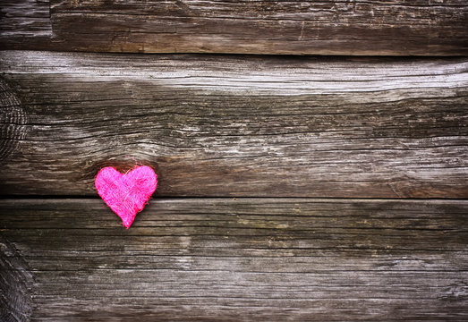 Decorative small heart on wooden old weathered background.