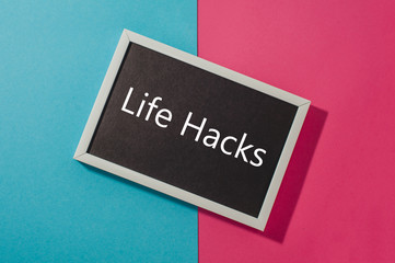 Life hacks - text on chalkboard on blue and pink bright background.